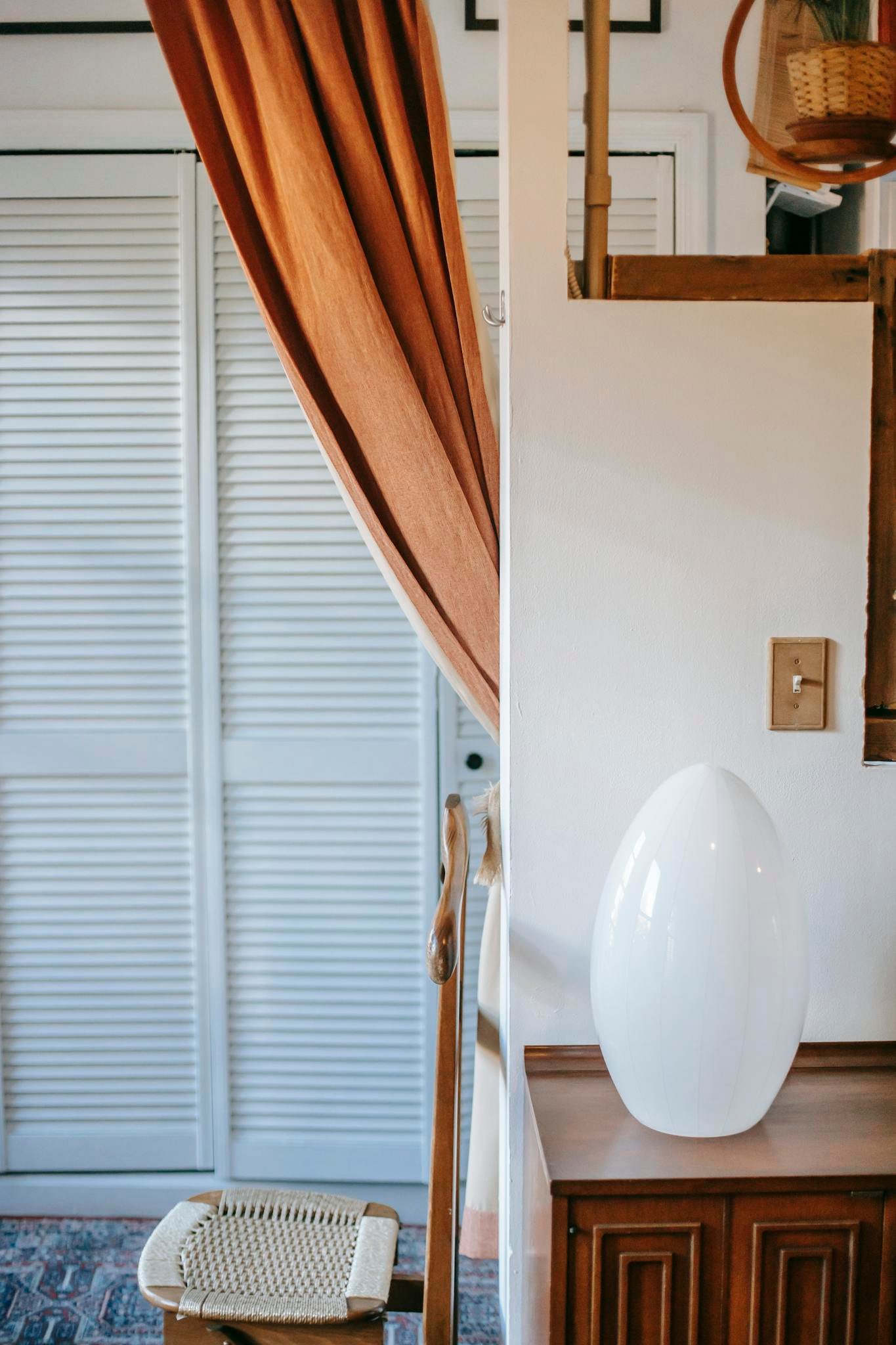 Elegant interior with a modern lamp, wooden furnishings, and vintage decor elements.